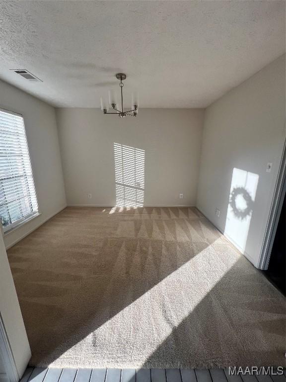 interior space with light colored carpet, a textured ceiling, and an inviting chandelier