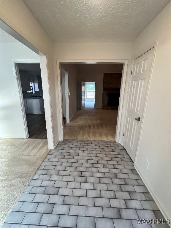 hall with light carpet and a textured ceiling