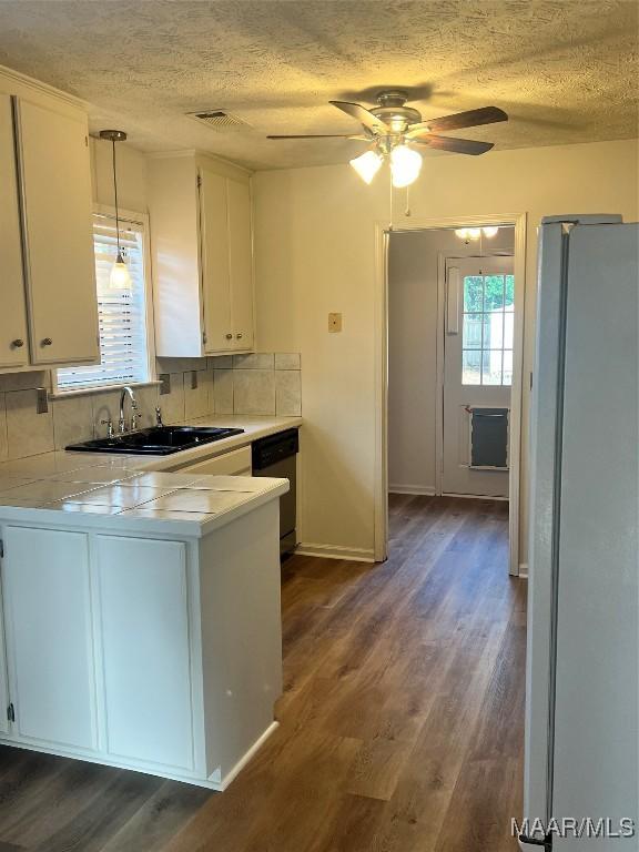 kitchen with white refrigerator, sink, decorative backsplash, decorative light fixtures, and white cabinetry