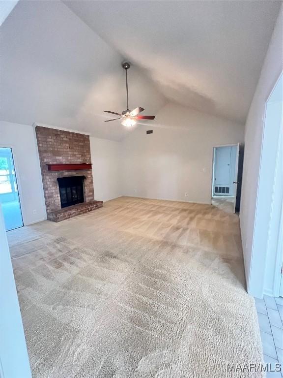 unfurnished living room with a fireplace, light colored carpet, vaulted ceiling, and ceiling fan