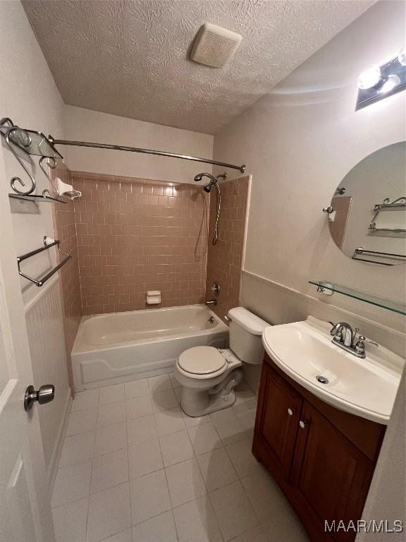 full bathroom featuring toilet, vanity, a textured ceiling, and tiled shower / bath combo