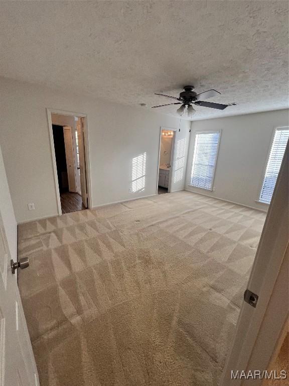 carpeted empty room with ceiling fan and a textured ceiling