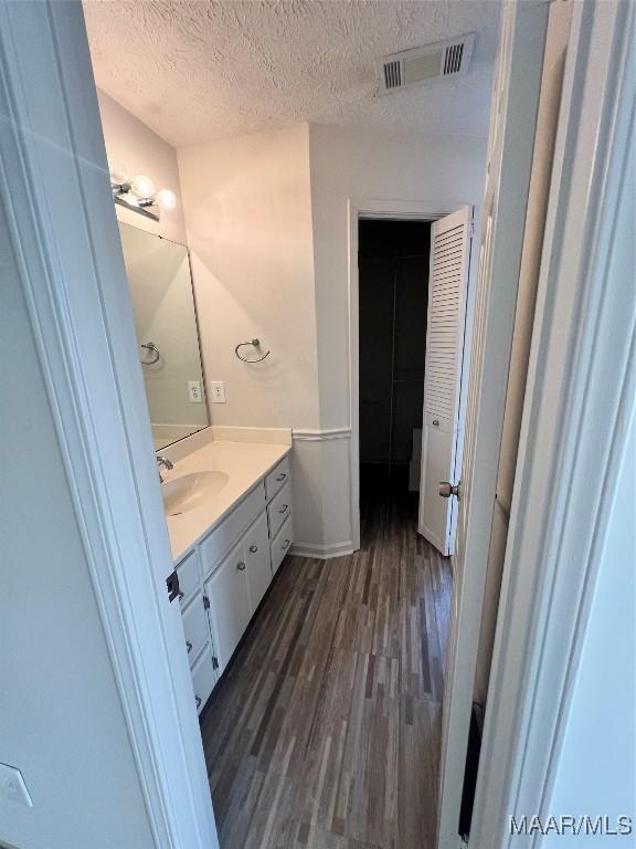 bathroom with vanity, a textured ceiling, and hardwood / wood-style flooring