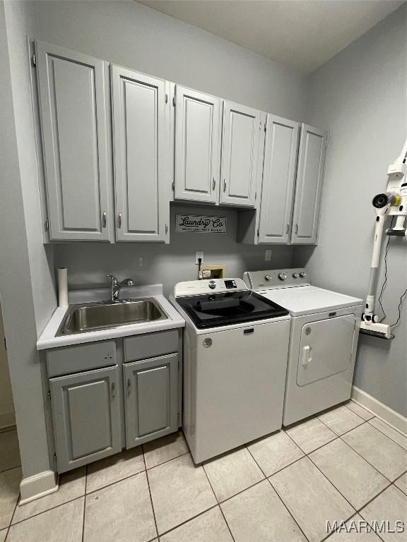 laundry area with cabinets, light tile patterned floors, washing machine and clothes dryer, and sink