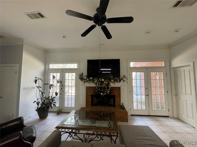 tiled living room featuring ceiling fan, french doors, crown molding, and a brick fireplace