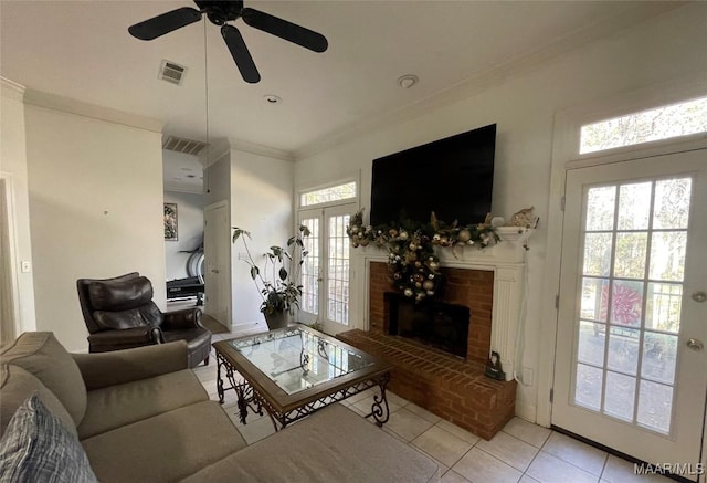 living room featuring a fireplace, ceiling fan, a healthy amount of sunlight, and light tile patterned flooring