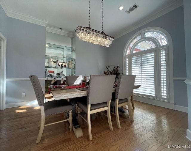 dining space featuring hardwood / wood-style floors, an inviting chandelier, and crown molding