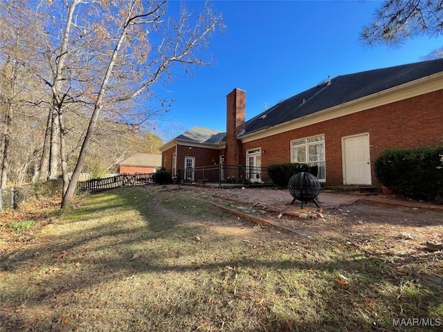 rear view of property featuring a yard and an outdoor fire pit