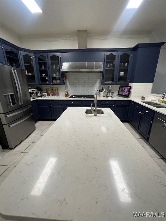 kitchen featuring blue cabinetry, sink, stainless steel appliances, extractor fan, and decorative backsplash