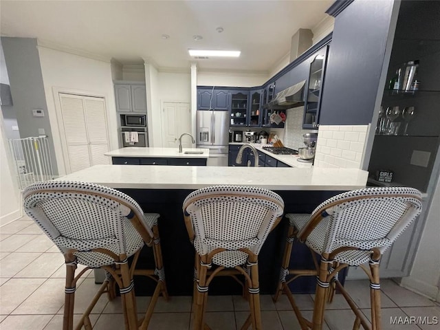 kitchen featuring sink, light tile patterned floors, appliances with stainless steel finishes, tasteful backsplash, and kitchen peninsula