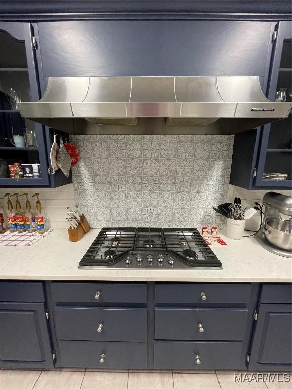 kitchen with decorative backsplash, light tile patterned flooring, stainless steel gas cooktop, and range hood