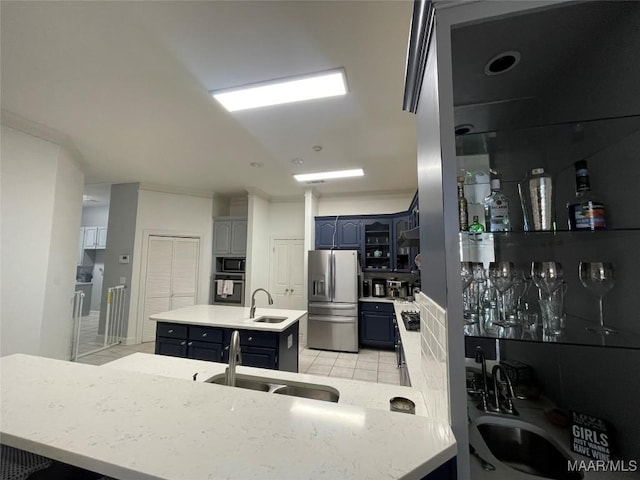 kitchen with light tile patterned floors, sink, stainless steel appliances, and an island with sink