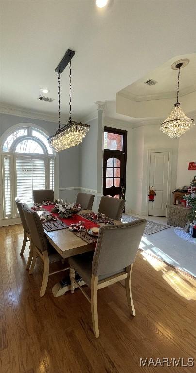 dining room with hardwood / wood-style floors, ornamental molding, and a chandelier