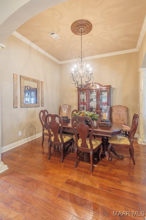 dining area featuring hardwood / wood-style floors, crown molding, and an inviting chandelier