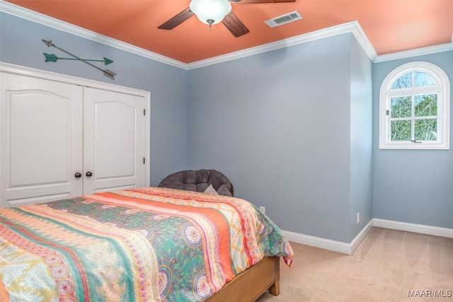 carpeted bedroom with ceiling fan, a closet, and crown molding