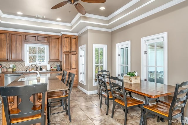 kitchen featuring ceiling fan, dishwasher, tasteful backsplash, crown molding, and a tray ceiling