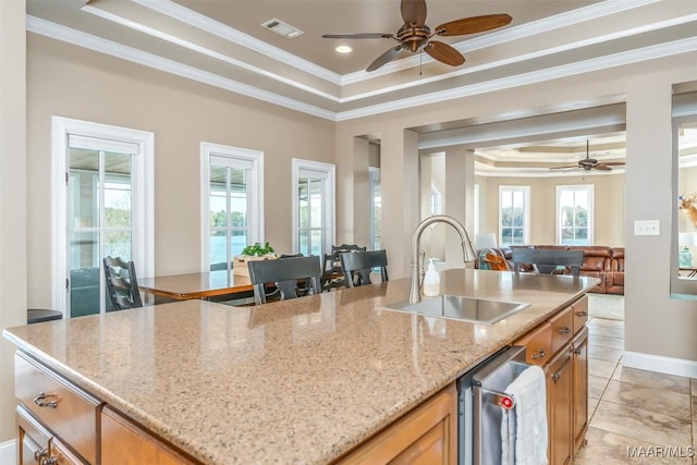 kitchen featuring a raised ceiling, crown molding, sink, ceiling fan, and light stone counters