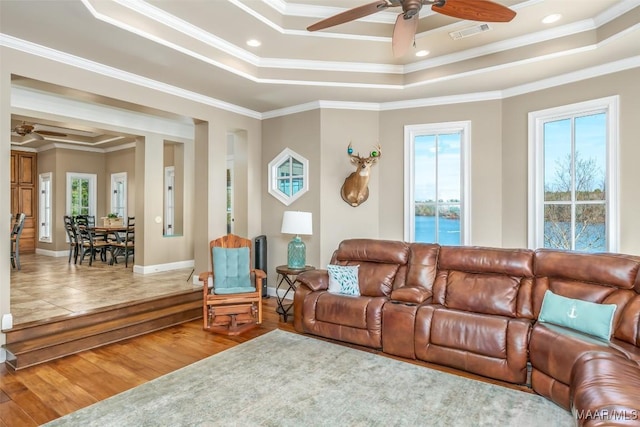 living room featuring hardwood / wood-style floors, a tray ceiling, ceiling fan, and ornamental molding