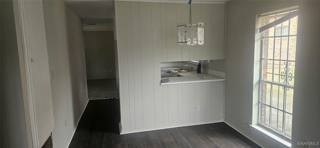 unfurnished dining area with a chandelier and dark wood-type flooring