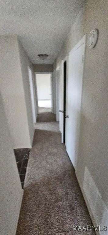 hallway featuring carpet floors and a textured ceiling