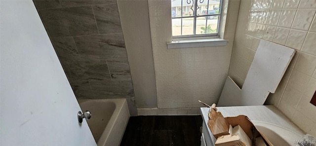 bathroom featuring a tub to relax in, tile walls, and hardwood / wood-style flooring