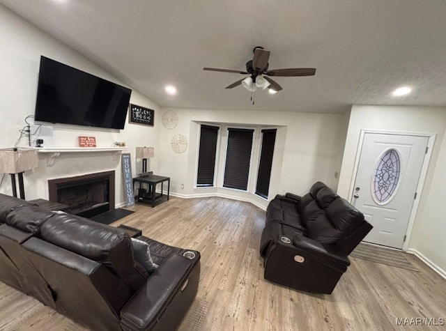 living room featuring ceiling fan, light hardwood / wood-style flooring, and a textured ceiling