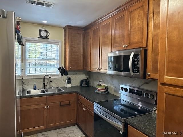 kitchen featuring dark stone counters, decorative backsplash, sink, and stainless steel appliances