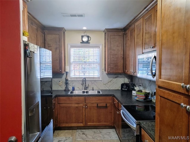 kitchen with backsplash, sink, dark stone counters, and appliances with stainless steel finishes