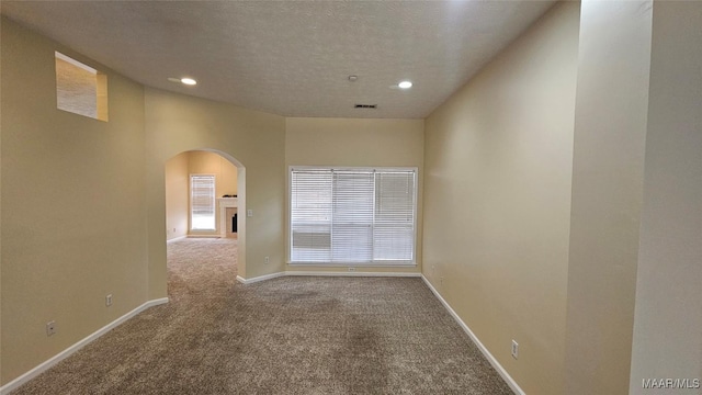 unfurnished room featuring carpet flooring, a textured ceiling, and vaulted ceiling