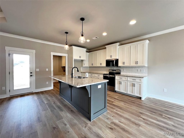 kitchen with white cabinetry, hanging light fixtures, a kitchen island with sink, light stone counters, and stainless steel appliances