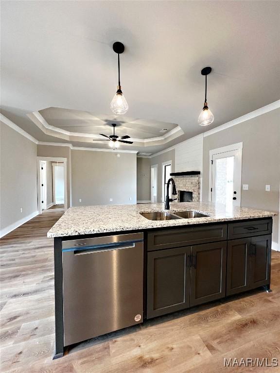 kitchen featuring decorative light fixtures, dishwasher, sink, and a tray ceiling