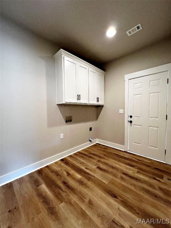 laundry room featuring dark wood-type flooring, cabinets, and electric dryer hookup