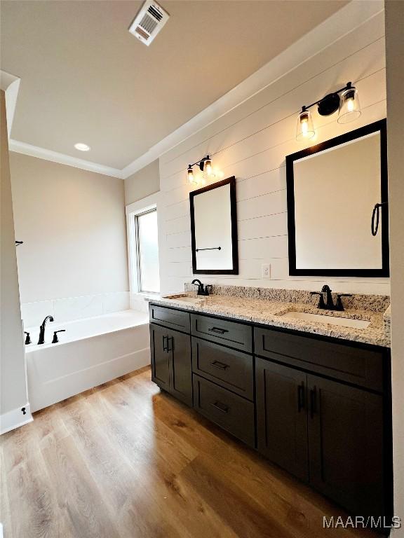 bathroom with vanity, hardwood / wood-style floors, crown molding, and a tub