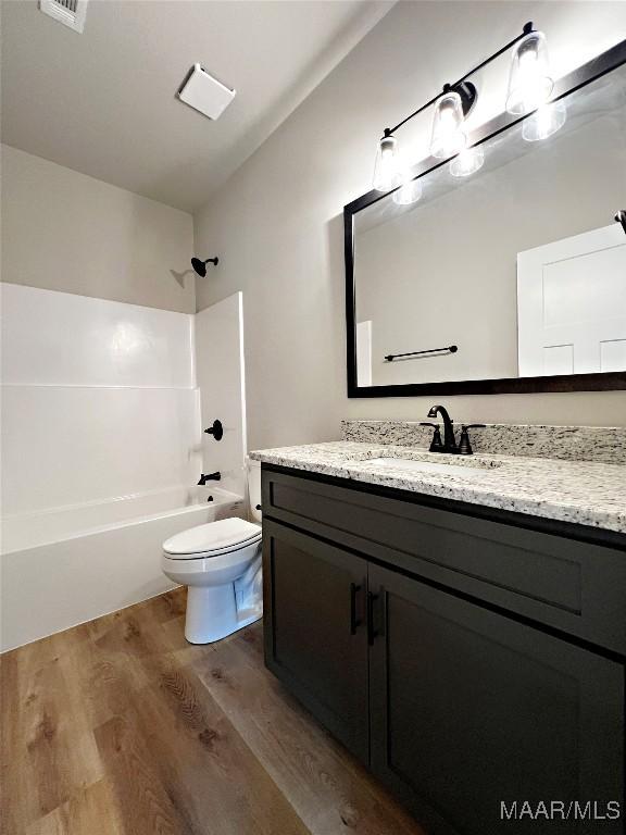 full bathroom featuring lofted ceiling, toilet, wood-type flooring, shower / bathtub combination, and vanity