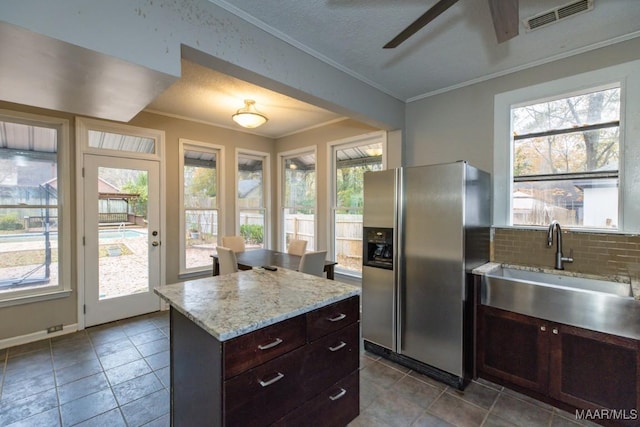 kitchen featuring sink, stainless steel fridge with ice dispenser, decorative backsplash, dark brown cabinets, and a kitchen island