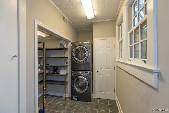 laundry room featuring stacked washer / drying machine, dark tile patterned floors, ornamental molding, and a textured ceiling