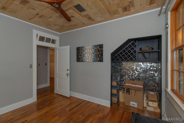 empty room featuring ceiling fan, ornamental molding, wood ceiling, and wood-type flooring