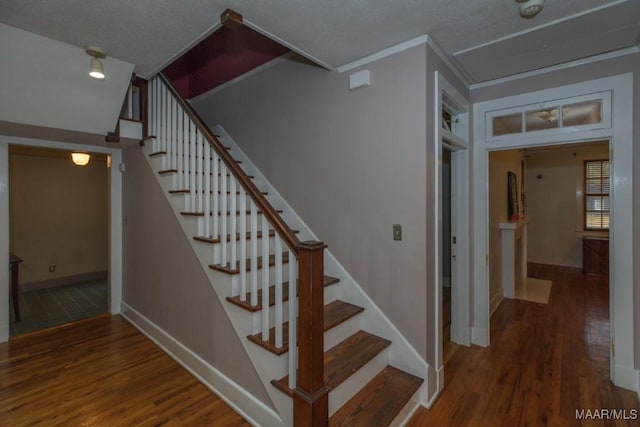 staircase featuring hardwood / wood-style flooring, ornamental molding, and a textured ceiling