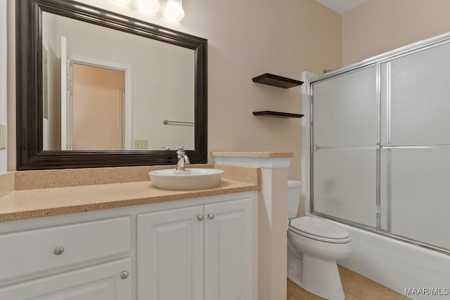 full bathroom featuring tile patterned floors, vanity, toilet, and enclosed tub / shower combo