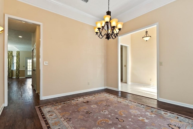 spare room featuring a chandelier, crown molding, and dark wood-type flooring