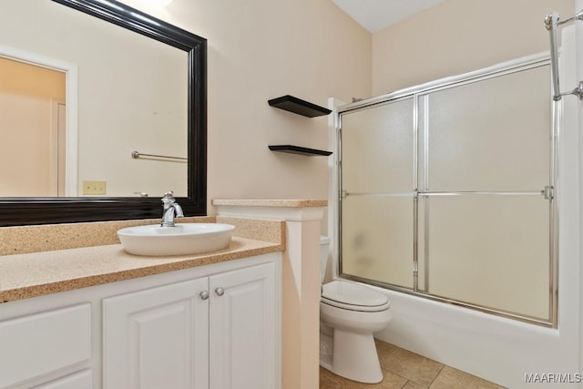 full bathroom with tile patterned flooring, vanity, combined bath / shower with glass door, and toilet