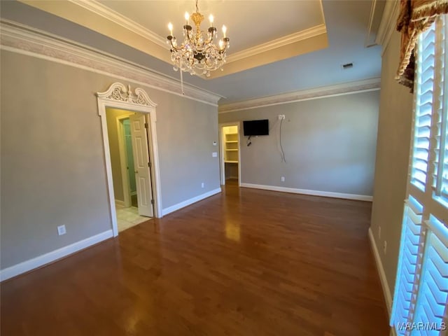 spare room featuring a tray ceiling, a chandelier, wood-type flooring, and ornamental molding