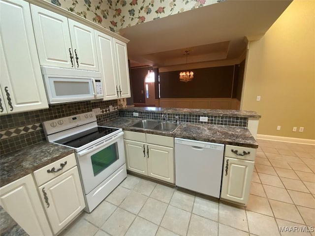 kitchen with sink, backsplash, kitchen peninsula, a chandelier, and white appliances