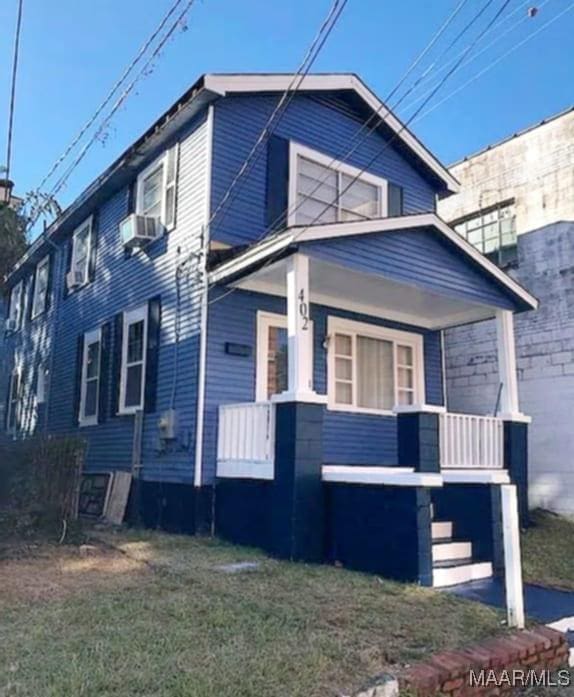 view of front facade with cooling unit, a front lawn, and covered porch