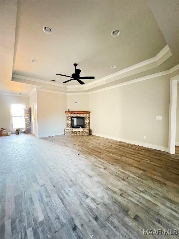 unfurnished living room with a raised ceiling, crown molding, and hardwood / wood-style floors