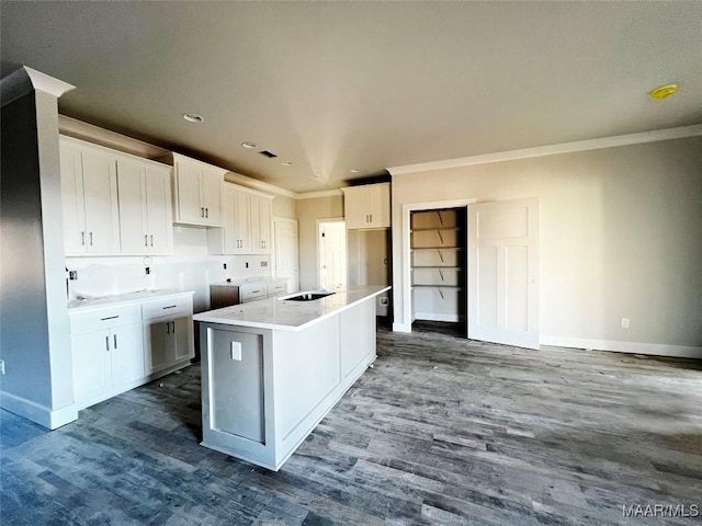 kitchen featuring a center island with sink, ornamental molding, wood-type flooring, and white cabinetry