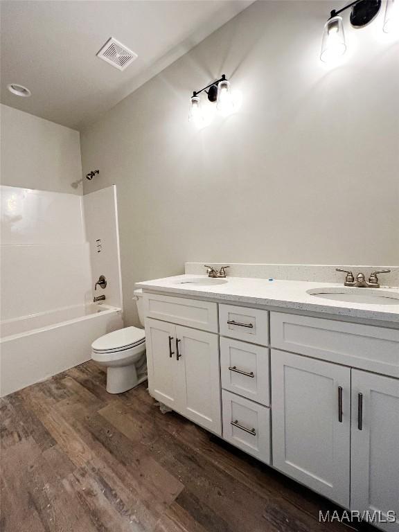 full bathroom with hardwood / wood-style floors, bathtub / shower combination, vanity, and toilet