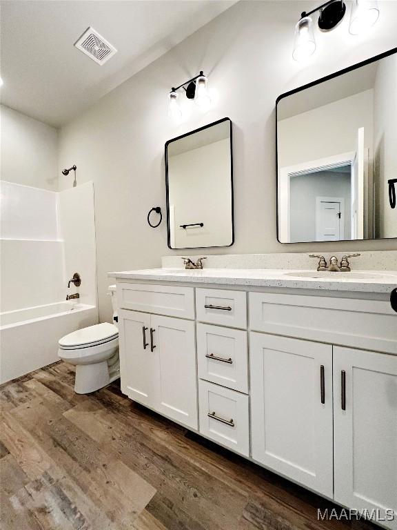 6 Village Knl, Wetumpka, AL 36093 - full bathroom with wood finished floors, double vanity, toilet, shower / bathtub combination, and visible vents