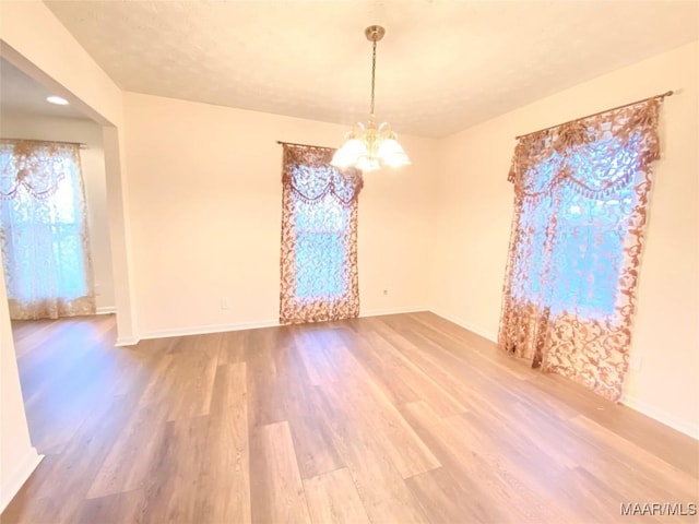 spare room featuring hardwood / wood-style flooring and a notable chandelier