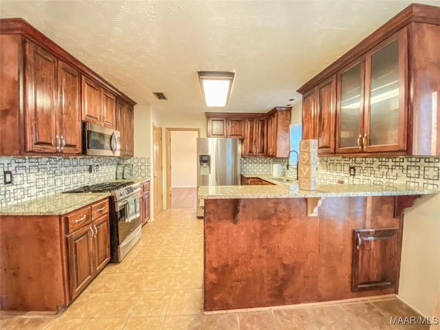 kitchen featuring a breakfast bar, sink, appliances with stainless steel finishes, tasteful backsplash, and kitchen peninsula